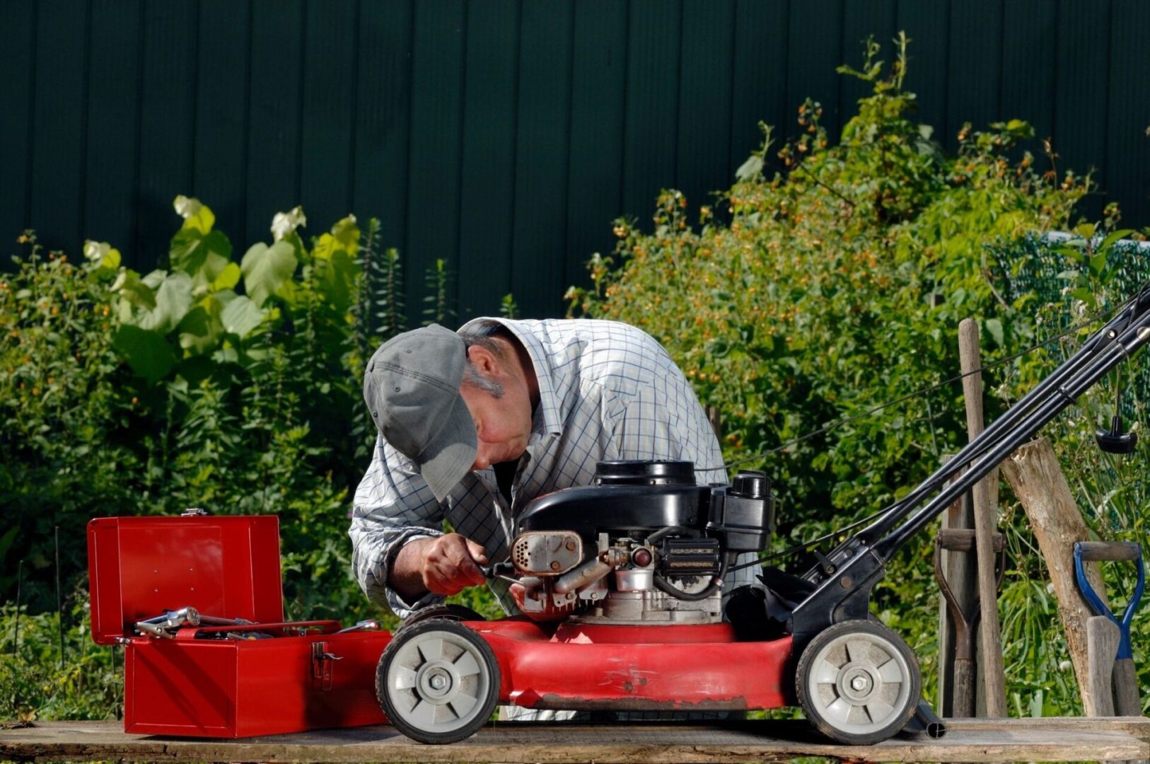 A man working on a red lawn mower.